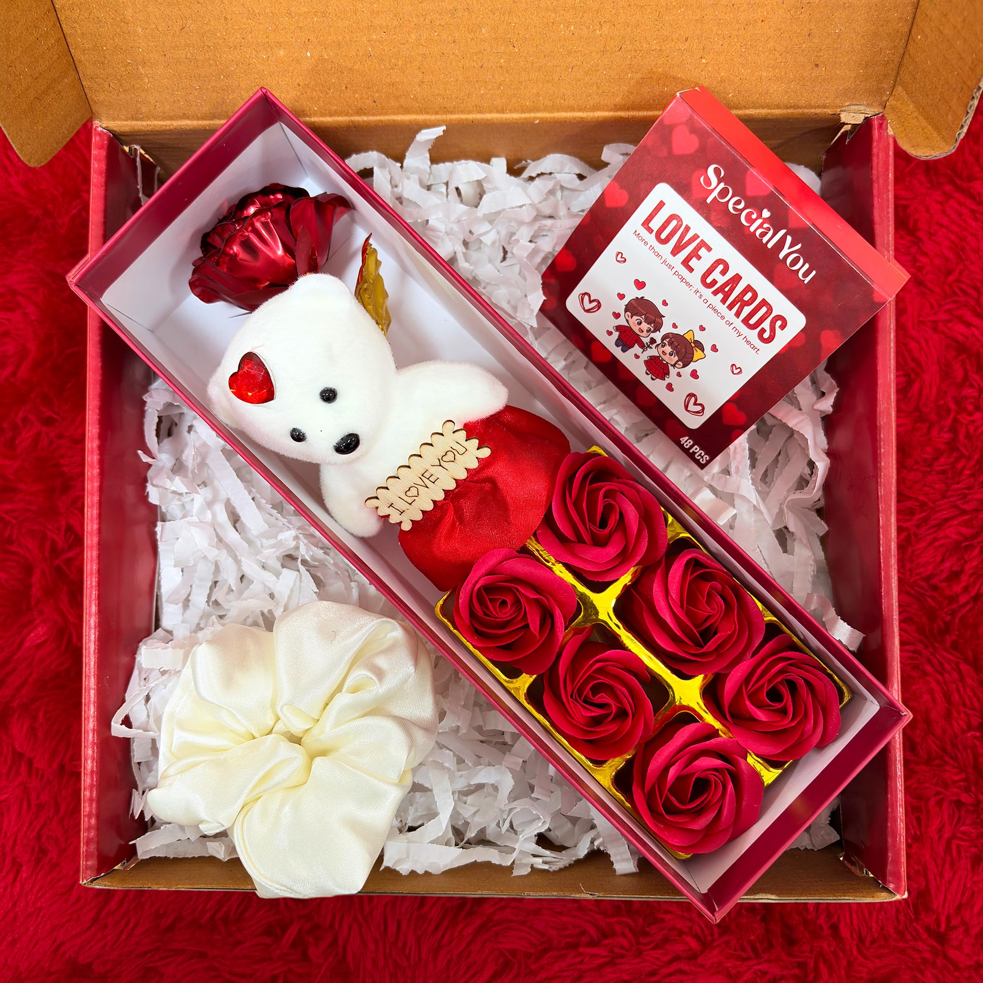 Gift set with red and white flowers, a small white bear, and love cards in a box.